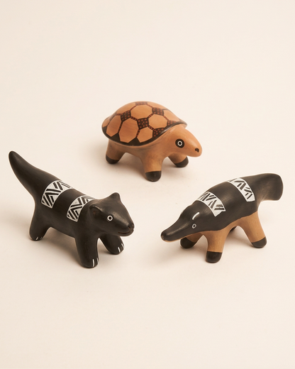 Duas figuras de animais e uma tartaruga de cerâmica Waura, com grafismos em preto, branco e tons de argila.